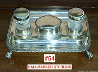 Front view of rectangular sterling silver tray with rope-edge, claw feet, two cut-glass inkwells with hinged lids and central oval lidded container