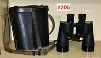 View of US Navy binoculars and matching black leather carrying case showing strap and buckle