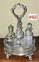 Full view of Victorian cruet stand holding six glass bottles with a silver-tone metal handle.