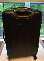 Closed rear view of Travelers Club black spinner suitcase showing handle and wheels.