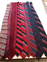 Nine men's ties neatly arranged side by side showing patterns and colors.