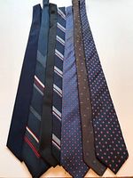 Seven men's ties laid flat showing various patterns and colors