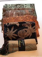 Six folded shawls stacked to show color and pattern variety including designs with leaves, flowers, and paisley motifs