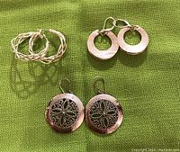 All three pairs of sterling silver earrings displayed on green fabric background, showing each style distinctly.