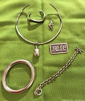 Full lot view showing all items laid out on green fabric: open cuff bracelet, collar necklace with oval pendant, rectangular Mexican pin, link bracelet, oval shaped bangle, and Kokopelli pin charm.