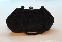 Front and side view of vintage black beaded bag with beaded handles and rhinestone clasp.