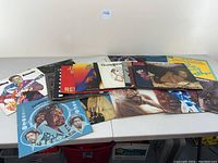 Overview of 15 vinyl records from 1950s to 1970s laid out on table showing album covers including BB King, Barry White, and others.
