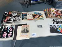 Overview photo of Beatles books, magazines, fan newsletters, pins and printed collectibles arranged on a table