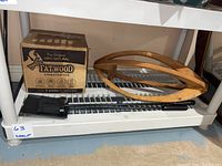 Photo showing a sealed box of Fatwood firestarters, black fireplace brush, black shovel, and wooden hanging planter on a shelving unit.