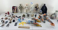 Wide assortment of 1990s Star Wars figures and large vehicles displayed on table including Boba Fett's Slave Ship and Podracers.