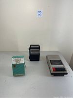 Three vintage portable electronic devices displayed together: turquoise Emerson 988 Rambler pocket radio, black GE Two Way transistor radio, and silver Daytron cassette recorder.