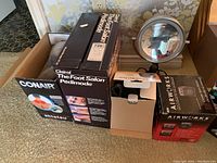 Boxed Clairol Foot Salon Pedimode foot spa, Conair massager, lighted makeup mirror, and Airworks space heater on carpeted floor.