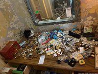 Full spread of earrings, necklaces, bracelets and red jewelry box on wood table under mirror
