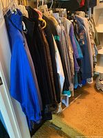 Photo of multiple jackets and tops hanging on a clothes rack in various colors including blue, black, tan and patterned.