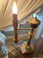 Single vintage swing arm candle style lamp on a glass table, brass finish, electric candle bulb lit.