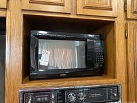 Side view showing full microwave oven in wood shelf with visible buttons and keypad