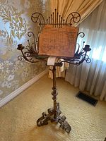 Full view of the ornate painted metal music stand showing scrollwork base, central column and lyre top