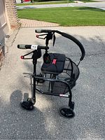 Side and angled view of black Nexus folding walker showing padded seat, metal basket, wheels and hand brakes.
