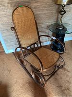 Full view of rocking chair showing caned backrest, seat and bent wood frame with rockers.