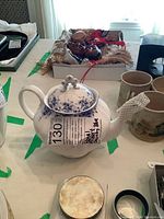 Front view of white porcelain teapot with lid and attached tag