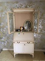 Front view of cream-painted secretary desk with hutch, both doors open showing decorative hardware