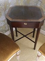 Front view of the octagonal lift top side table showing glass inset and brass keyhole on drawer front.