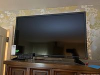 Front view of Toshiba TV on stand with remote control in front.