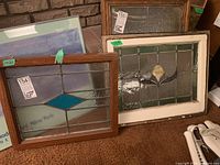 Two vintage stained glass windows side by side, showing distinct designs and wood framing.