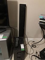 Soundbar standing vertically behind subwoofer on carpet beside TV stand
