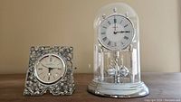 Two quartz clocks: one Seagull with ornate floral frame, one Bulova under glass dome