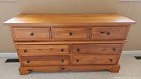 Front view of the wooden dresser showing three smaller drawers on top and three larger drawers below, metal round knobs and one cup pull handle on a top drawer, wood finish with scratches.