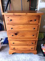 Front view of pine dresser showing four drawers with black knobs, some wear and scratches on the surface.