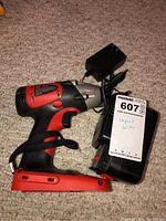 Impact driver with attached battery and charger set on carpet.