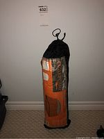 Photo showing the Eagle's Camp net tent packed in its black and orange carrying bag with branding and product information.