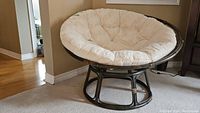 Side view of papasan chair showing rattan frame and beige faux fur cushion.