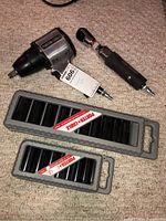 Two Porter-Cable pneumatic tools along with two labeled impact socket holders with sockets inside on carpet.
