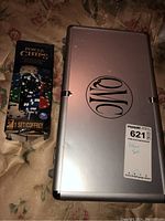 Closed aluminum poker chip carrying case with QMC logo, labeled with lot sticker and note 'Poker set'