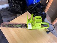 Full side view of Poulan electric chainsaw with 16 inch bar and attached power cord on a wooden table in garage.