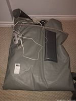 Folded grey sauna wrap with controller wired attached, laid on floor.