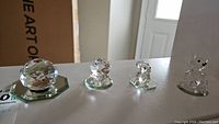 Four faceted Swarovski crystal figurines on bases including an oyster, bunny, and two bears.