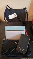 Overall view of the leather handbags and wallets laid out with visible brand label on black wristlet wallet.