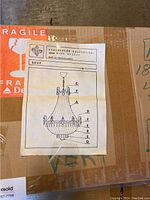Closed cardboard box with Fragile sticker and printed diagram of chandelier model 5027