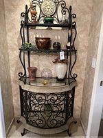 Full frontal view of the wrought iron shelving unit with glass shelves and decor