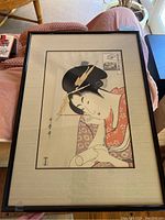 Framed woodblock print of a Japanese woman in traditional attire, showing full view of the print and frame.
