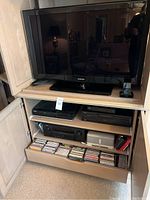 Front view of cabinet with Samsung TV, players, receiver and CDs
