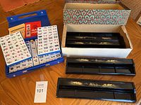 Overall lot on table: blue case open with tiles, instruction booklet, outer cardboard box and two lacquered racks