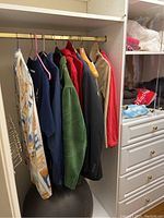 Closet section with hanging jackets and sport coats in various colors hung on hangers.