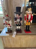 Three nutcracker figures on display: mouse king, gentleman with top hat, and soldier with gold crown.