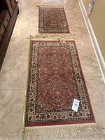 Two Persian rugs laid on tile floor, showing their full pattern.