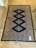 Top-down view of the full Persian rug showing central zigzag pattern in black and beige tones with geometric border.